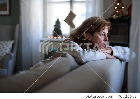 Lonely senior woman sitting on sofa indoors at Christmas, solitude concept. 70120515