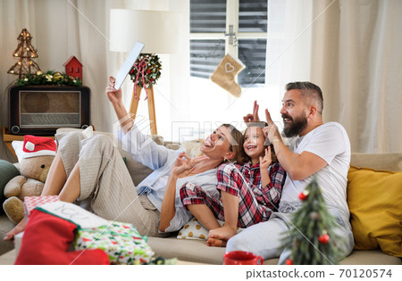Family with small daughter indoors at home at Christmas, having video call. Family with small daughter indoors at home at Christmas, having video call. 70120574