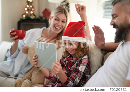 Family with small daughter indoors at home at Christmas, having video call. 70120581