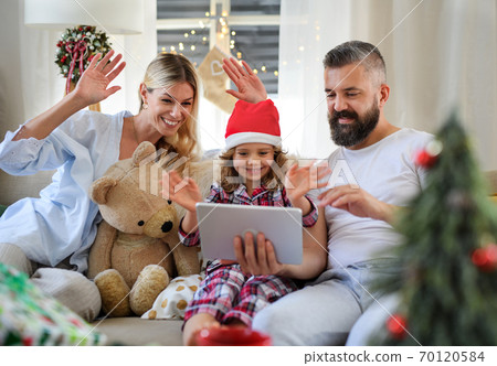 Family with small daughter indoors at home at Christmas, having video call. Family with small daughter indoors at home at Christmas, having video call. 70120584