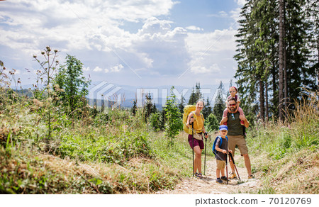 Family with small children hiking outdoors in summer nature. 70120769