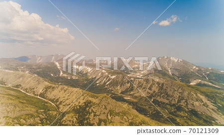 Green forest among the red mountains in the Magadan region. 70121309