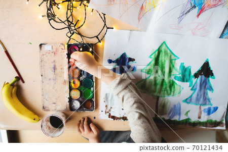 Top view of unrecognizable small child indoors at home at Christmas, painting pictures. Top view of unrecognizable small child indoors at home at Christmas, painting pictures. 70121434