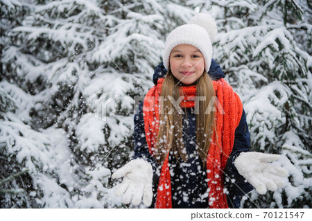 A playful teenage girl with a beautiful smile throws snow flakes and rejoices at the onset of the long-awaited winter. A playful teenage girl with a beautiful smile throws snow flakes and rejoices at the onset of the long-awaited winter. 70121547