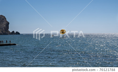 Water recreation. Launch a skydiver on a yellow parachute with a painted smile. 70121788