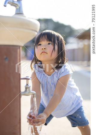 Girl washing hands in the water in the park 70121995