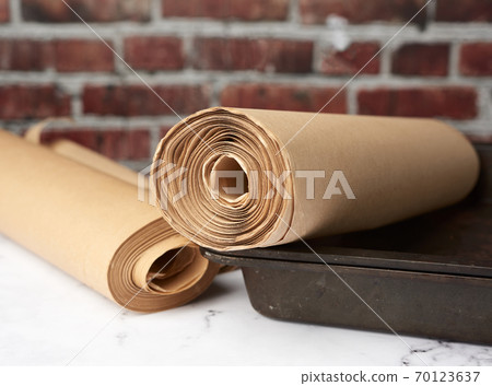 metal pan and rolls of brown parchment paper on a white table metal pan and rolls of brown parchment paper on a white table 70123637