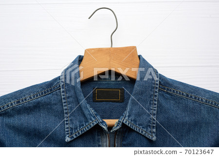 blue denim shirt hanging on vintage wooden hanger, white background 70123647