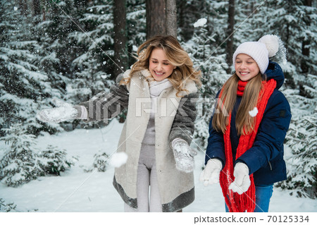 Beautiful young blonde with her charming daughter enjoy the snow outside the city in the forest Beautiful young blonde with her charming daughter enjoy the snow outside the city in the forest 70125334