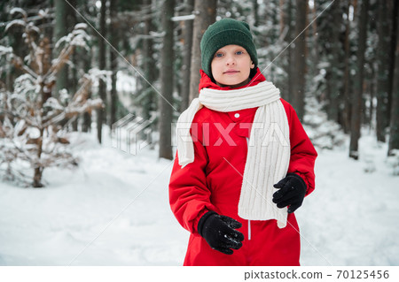 Portrait of a boy in a red jumpsuit with a scarf in a winter snow forest Portrait of a boy in a red jumpsuit with a scarf in a winter snow forest 70125456