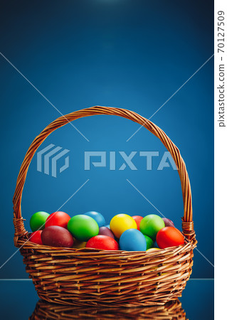 Easter color eggs in festive gift basket, blue background 70127509