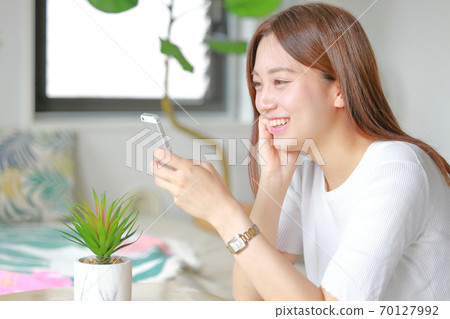 觀看有微笑的婦女一個智能手機 70127992