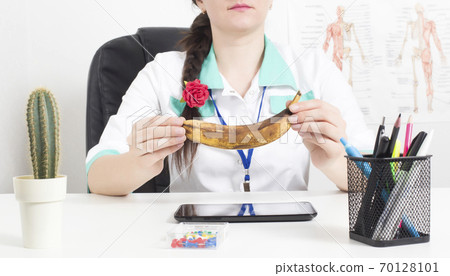 Doctor urologist andrologist holds a spoiled banana in his hands. The concept of male diseases, male menopause, ejaculation disorders 70128101