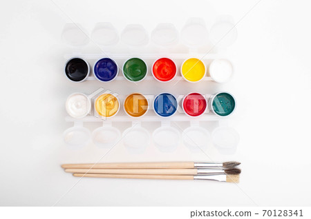 A set of watercolor paints on a white background and brushes for painting. 70128341