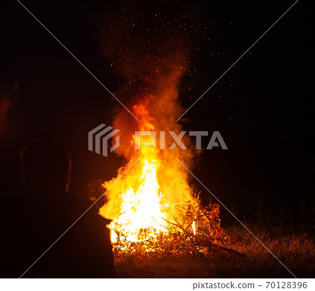 Beautiful big bonfire in the forest at night. A man looks at a bonfire, outdoor recreation, background, tourist 70128396