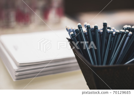 pens and pencils with an eraser on the end on the background of a stack of papers 70129685