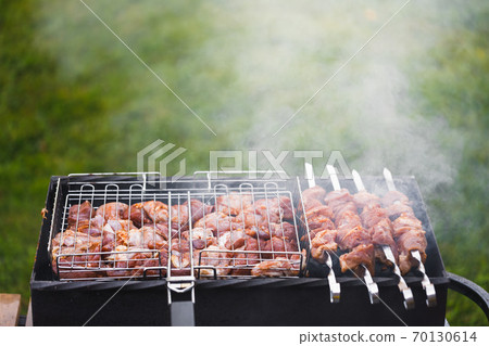 grill barbecue meat on a brazier with smoke, green grass background grill barbecue meat on a brazier with smoke, green grass background 70130614