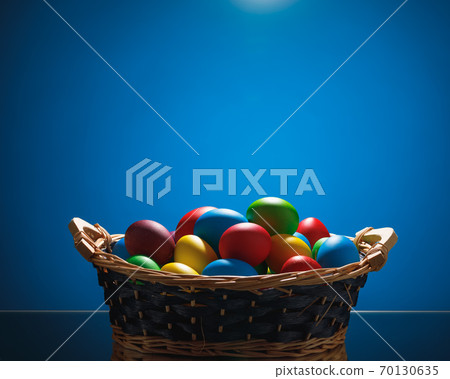 Easter color eggs in festive gift basket, blue background Easter color eggs in festive gift basket, blue background 70130635