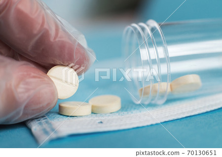 medical tablets close on the blue background.paramedic hand holds pill. Coronavirus, flu respiratory disease concept 70130651