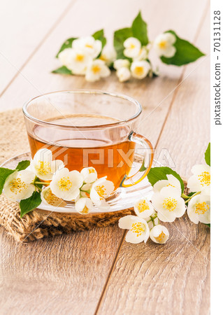 Glass cup of green tea with white jasmine flowers 70131128