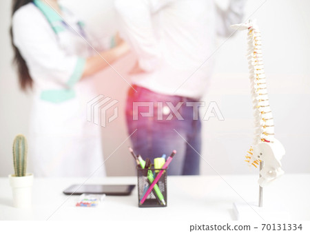 Male patient at the appointment with a doctor vertebrologist. Diagnosis and treatment of back pain diseases, background. Dislocation and trauma of the intervertebral disc, pinched nerve Male patient at the appointment with a doctor vertebrologist. Diagnosis and treatment of back pain diseases, background. Dislocation and trauma of the intervertebral disc, pinched nerve 70131334