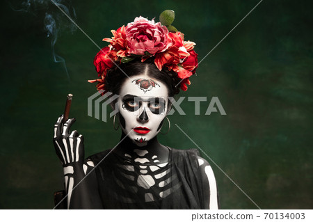 Young girl in the image of Santa Muerte, Saint death or Sugar skull with bright make-up. Portrait isolated on studio background. Young girl in the image of Santa Muerte, Saint death or Sugar skull with bright make-up. Portrait isolated on studio background. 70134003