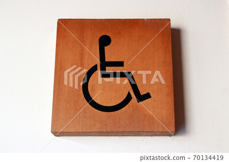 Wooden handicapped mark on the wall in front of the Bathroom disabled. 70134419