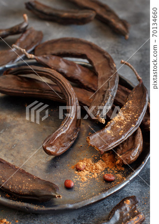 Dry carob pods and powder close up 70134660