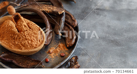 Dry carob pods and powder close up 70134661