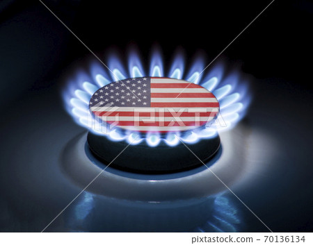 Burning gas burner of a home stove in the middle of which is the flag of the country of USA. Gas import and export delivery concept, price per cubic meter, transit, background 70136134