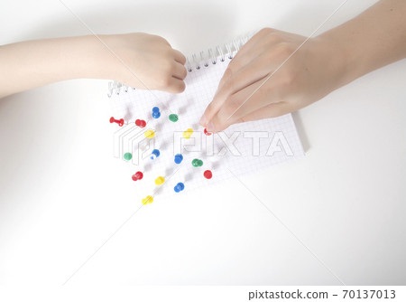 The hand of a child and a doctor sets multi-colored pins in a leaf on a white background. Autism development concept of a child thinking in games, autism, neurosonography The hand of a child and a doctor sets multi-colored pins in a leaf on a white background. Autism development concept of a child thinking in games, autism, neurosonography 70137013