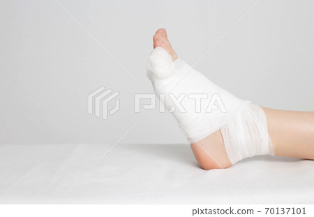 Man's bandaged foot with little finger on a white background. The concept of a fracture of the little finger on the leg with offset, copy space, deformation Man's bandaged foot with little finger on a white background. The concept of a fracture of the little finger on the leg with offset, copy space, deformation 70137101