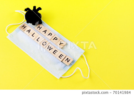 Black toy spider, medical mask and words Happy Halloween on yellow. Halloween background decor holiday concept 70141984