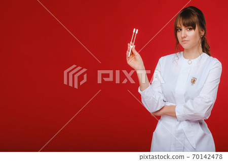 Beautiful girl doctor with a tuning fork stands Beautiful girl doctor with a tuning fork stands 70142478