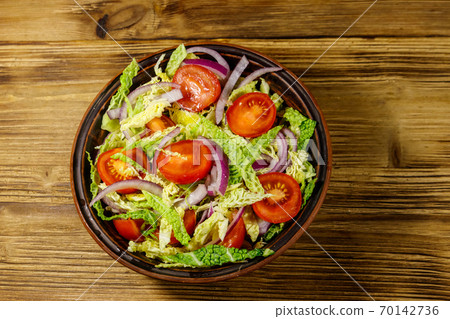 Healthy salad with savoy cabbage, cherry tomato, red onion and olive oil on wooden table. Top view Healthy salad with savoy cabbage, cherry tomato, red onion and olive oil on wooden table. Top view 70142736