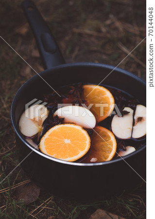 Spicy mulled wine with orange, apples, cinnamon and anise in a pot 70144048