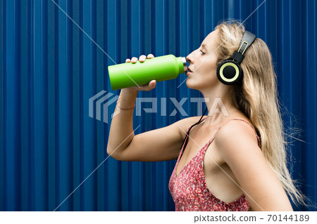 Happy girl drink fresh spring water from green reusable bottle Happy girl drink fresh spring water from green reusable bottle 70144189