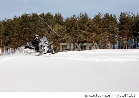 In deep powder snowdrift snowmobile rider driving fast. 70144198