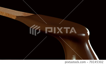 Wooden spoon stirring soft melted rich chocolate 70145302