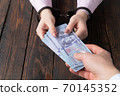 men's hands give money to women's hands in handcuffs against the background of a wooden table 70145352