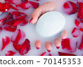 Female hand hold soap against the background of milk or white water with rose petals 70145353