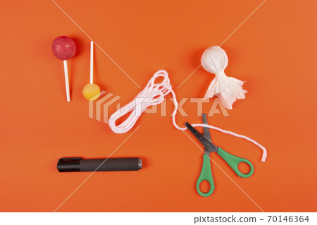 Halloween DIY concept. Make a cute ghost out of candy on a stick 70146364