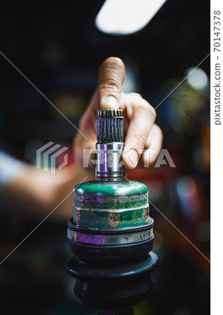 hand holding ATV constant-velocity CV joint, repair in old garage 70147378
