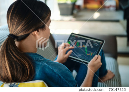 Woman Trading Online Using Tablet Computer On Sofa Woman Trading Online Using Tablet Computer On Sofa 70147833