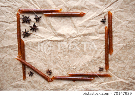 Rolled fruit pastila sticks and star anise spices frame composition on beige paper background Rolled fruit pastila sticks and star anise spices frame composition on beige paper background 70147929