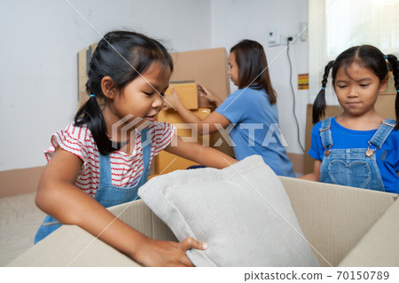 Two asian child girls helping parents put on stuff into the box on moving day. Home renovation and relocation concept. 70150789