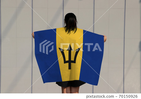 Woman holding Barbados flag on her shoulder and turn back on grey background. 70150926