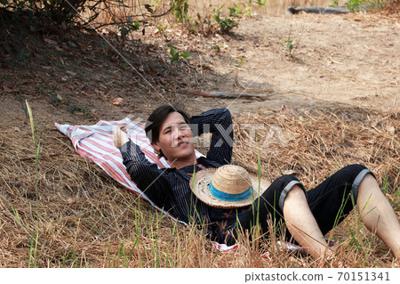 Agriculturist male use the loincloth on the floor for laying relax with a hat on him at nature. Agriculturist male use the loincloth on the floor for laying relax with a hat on him at nature. 70151341
