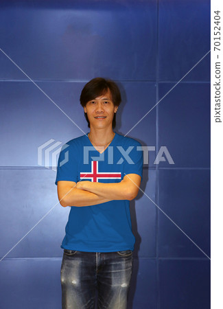 Man wearing Iceland flag pattern shirt and cross one's arm on the blue wall background. 70152404