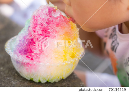 Girl chewing on colorful shaved ice 70154219